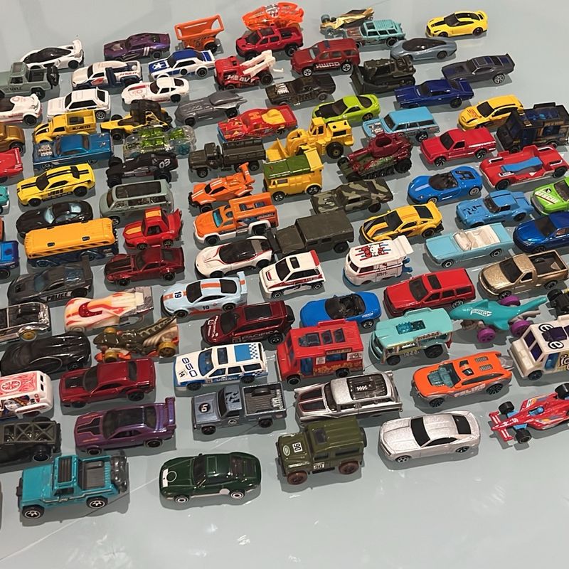 Coleção de dezenas de carrinhos em miniatura coloridos, vistos de cima