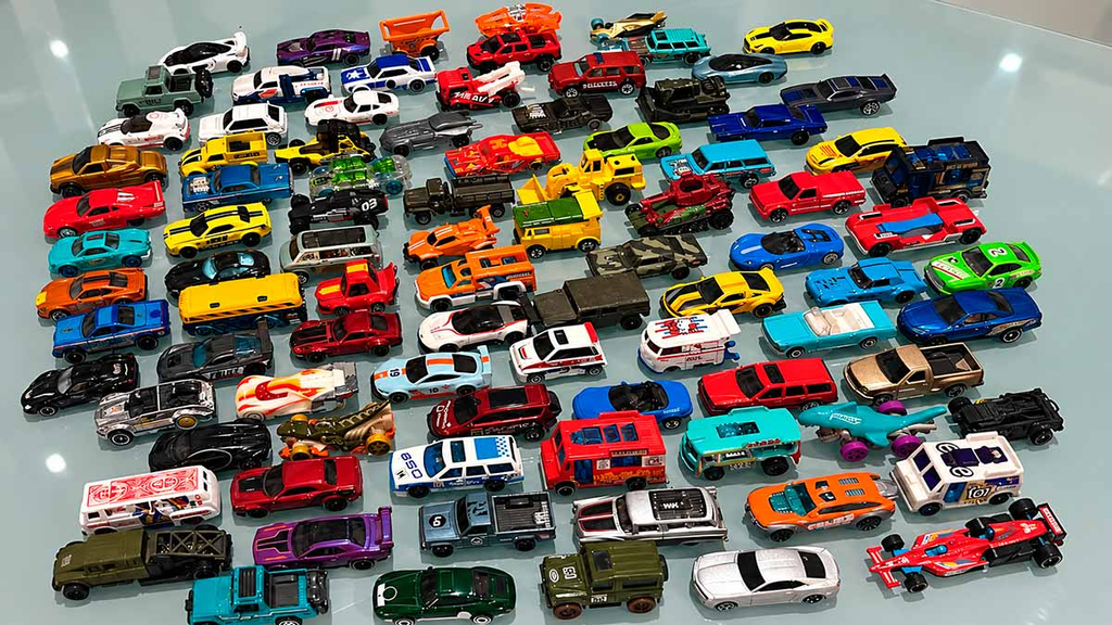 Coleção de carrinhos em miniatura de diferentes modelos e cores, incluindo carros esportivos, caminhões e veículos especiais.