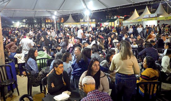 Público sentado às mesas sob a tenda do festival
