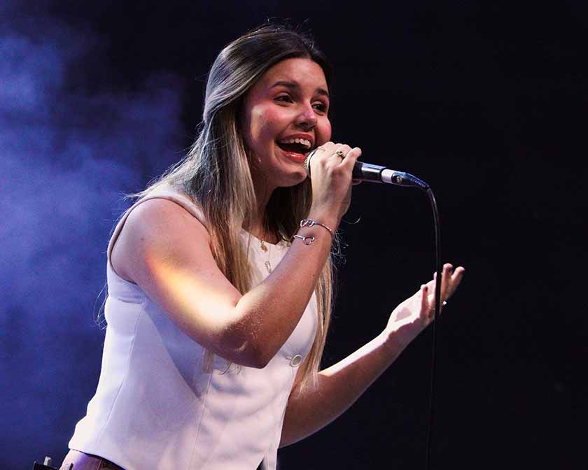Isadora Rizzardi cantando com o microfone na mão durante uma apresentação