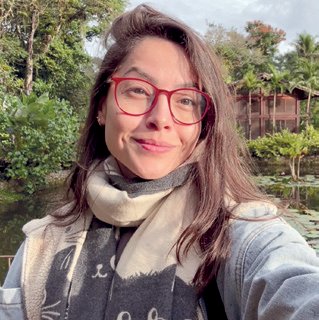 Retrato de Naioma, professora de yoga, de óculos e cachecol, sorrindo